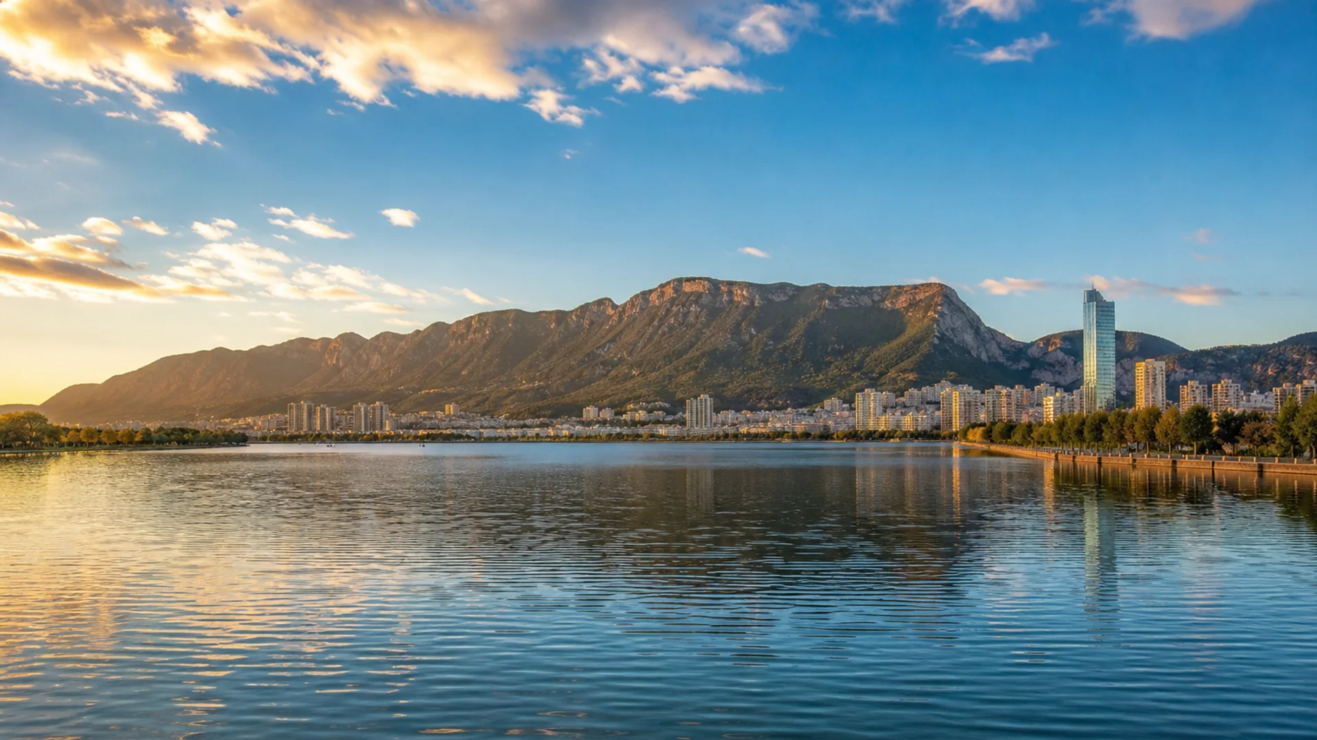 Kunming skyline and Western Hills reflected across Dianchi Lake at golden hour